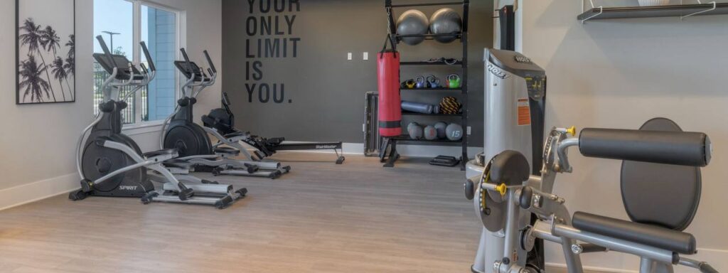 A gym with exercise bikes, weight machines, a punching bag, and yoga balls. A motivational quote on the wall reads, "Your only limit is you.